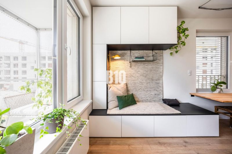 A bright interior of a 3-room apartment with a cozy reading nook and a floor with a wooden decor.