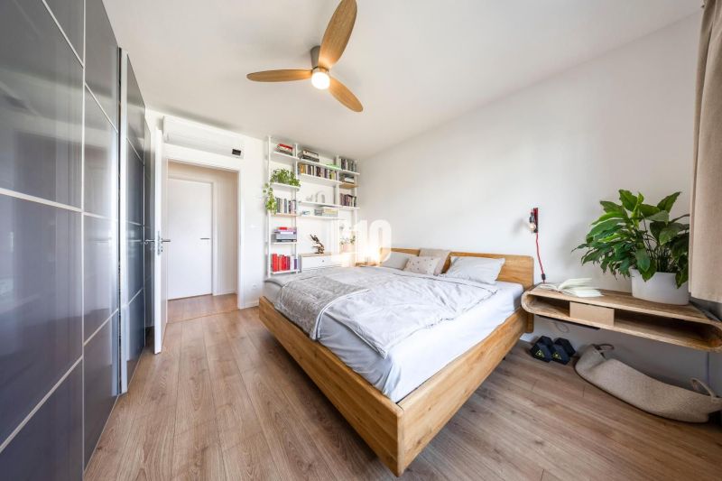 A bright bedroom in a three-room apartment with a wood-decor floor and modern furniture.