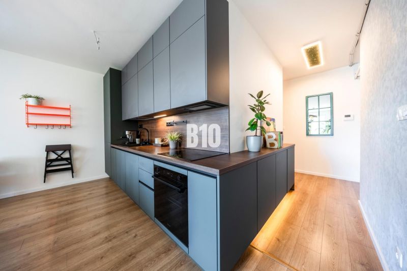 A kitchen unit in a 3-room apartment with a wooden decor floor and plants.