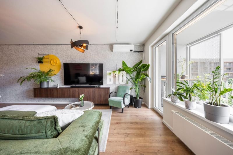 Living room in a 3-room apartment with a wooden decor floor and lots of plants.