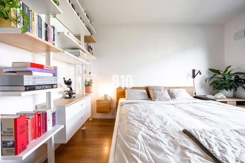 A bright bedroom with built-in shelves and a wooden decor floor in a 3-room apartment.