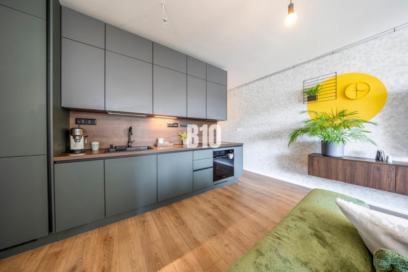 A kitchen in a 3-room apartment with dark cabinets, a wooden decor floor, and yellow decorations.