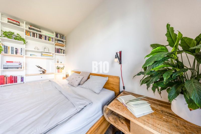 A cozy bedroom with a bookshelf, plants, and wooden furniture in a 3-room apartment.