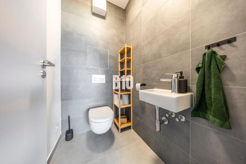 A bathroom in a 3-room apartment with modern gray tiles and a wall-mounted toilet.
