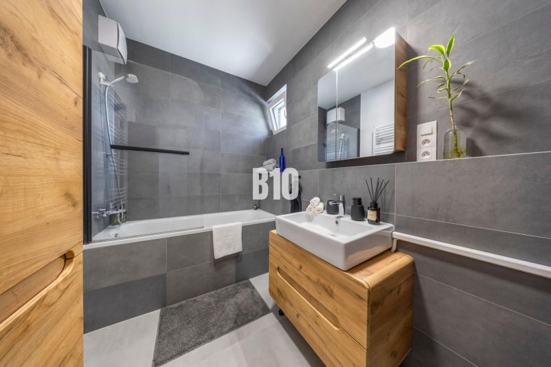 A bathroom with gray tiles and a wooden decor floor in a 3-room apartment.