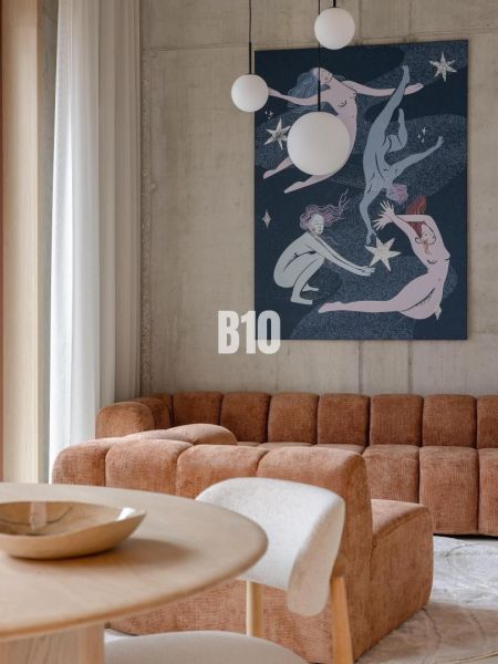 A bright living room with a sofa, striking art, and pendant lights in a two-room apartment.