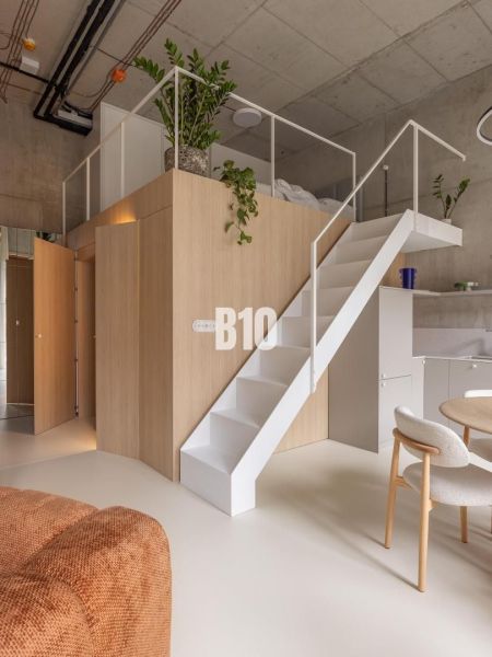 Interior of a 2-room apartment with a loft structure, a sofa set, and a floor with a wooden decor.