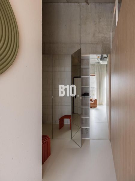 A hallway in a 2-room apartment with a concrete wall and mirrored doors.
