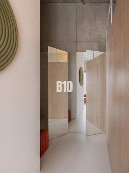 Mirror wall and wooden decorations in a 2-room apartment with a concrete ceiling.