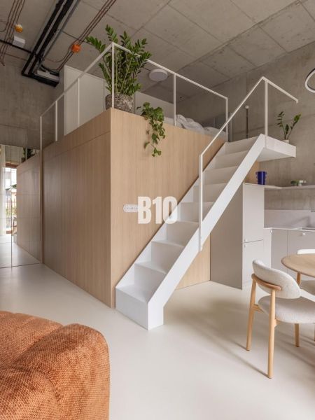 A duplex in a 2-room apartment with a wooden decor floor and a staircase.