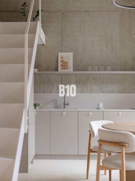 The kitchen part of a 2-room apartment with a minimalist design and a concrete wall.