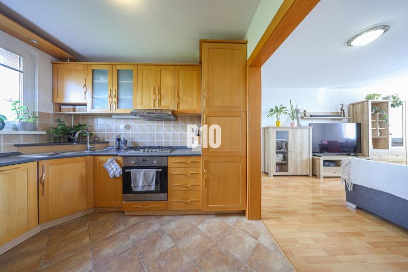 A kitchen in a 3-room apartment with a wooden decor floor and light furniture.