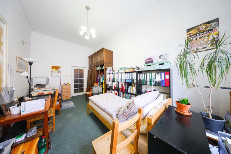 Room with a bed, shelves with documents, a desk, and a plant in a two-room apartment.
