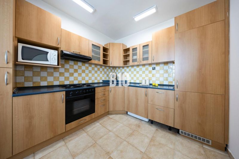 A kitchen with wooden cabinets and tiles in a 3-room apartment.