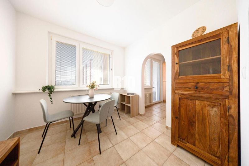 Dining area with a table, chairs, and a wooden cabinet in a 3-room apartment.