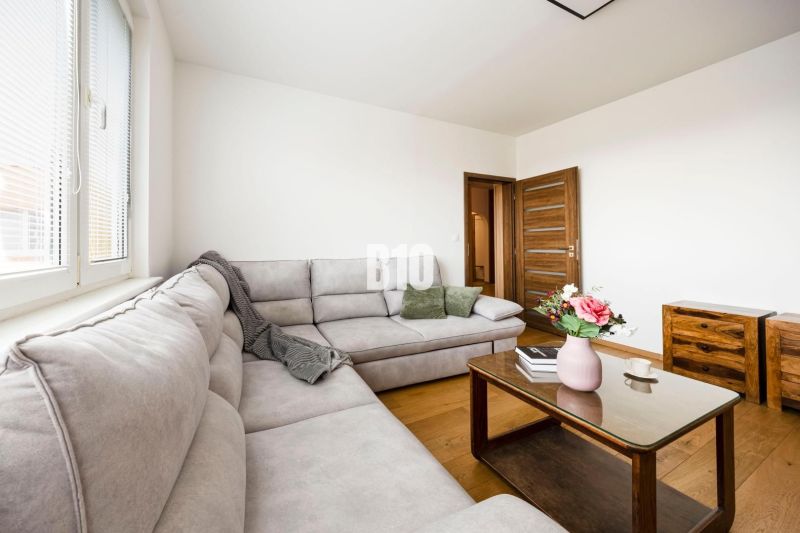 Living room in a 3-room apartment with a comfortable sofa and a wooden-patterned floor.