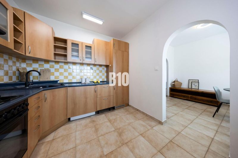 A kitchen with wooden cabinets and light tiles in a three-room apartment.