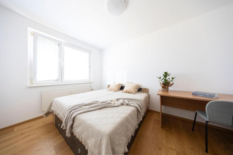 A bedroom in a 3-room apartment with a bed, table, and floor with a wooden decor.