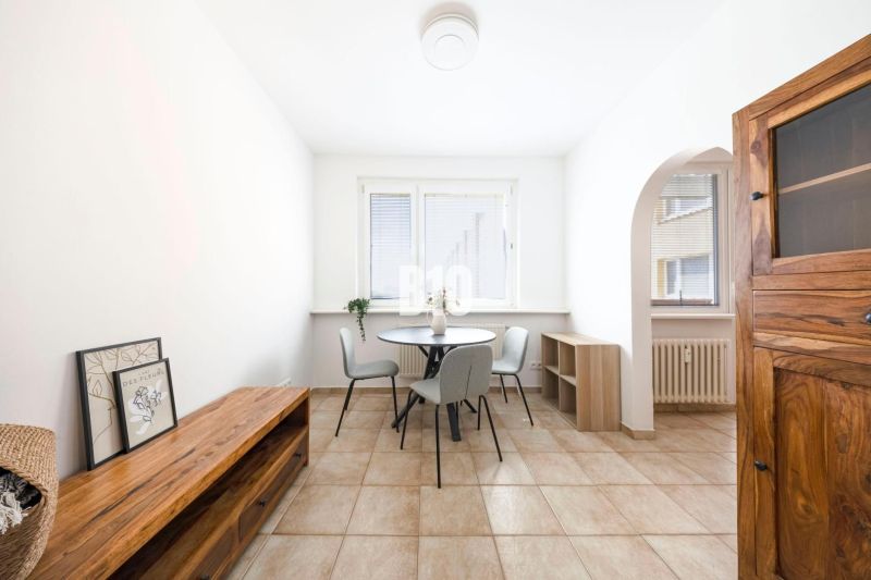 Dining area with a table and chairs in a 3-room apartment, tiled floor.