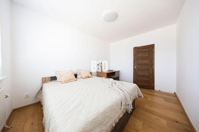 A bedroom with a wooden decor floor in a 3-room apartment, simple furniture and a bed.