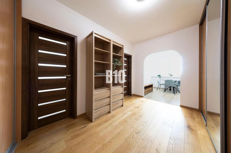 A hallway of a 3-room apartment with a shelving cabinet and a floor with a wooden decor.