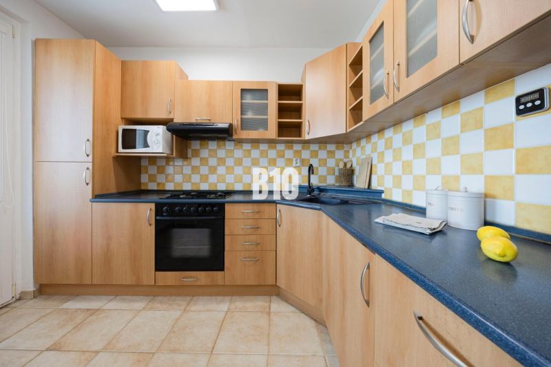 Kitchen unit with storage space, microwave, stove, and tiled backsplash in a 3-room apartment.