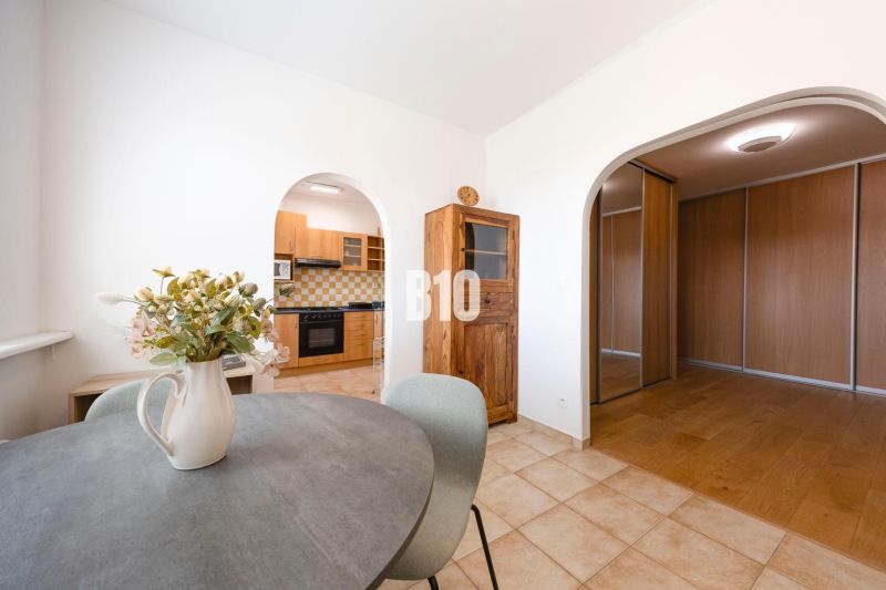 Dining and kitchen area in a 3-room apartment with wood-patterned flooring.