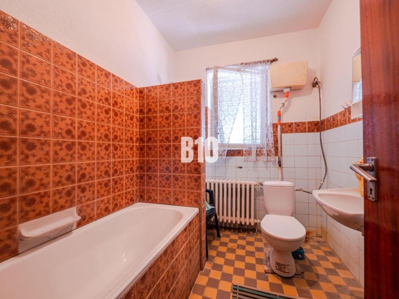 A bathroom in a family house with colorful tiles and a bathtub.
