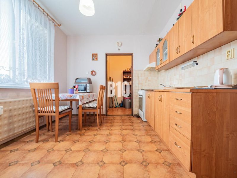 A kitchen in a 3-room apartment with wooden cabinets and a dining nook.