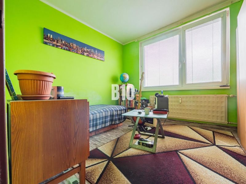 A room in a 3-room apartment with a colorful carpet and green walls, wooden furniture.