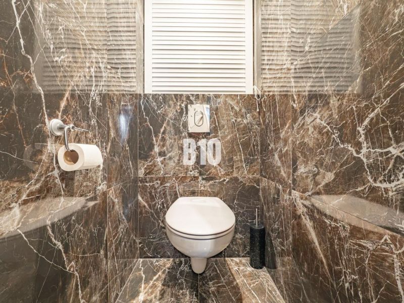Luxury bathroom in a 3-room apartment with marble tiles and a toilet.