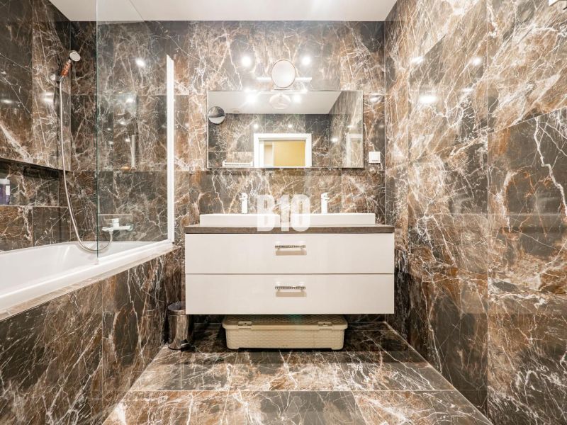 Elegant bathroom with marble tiles and a bathtub in a 3-room apartment.