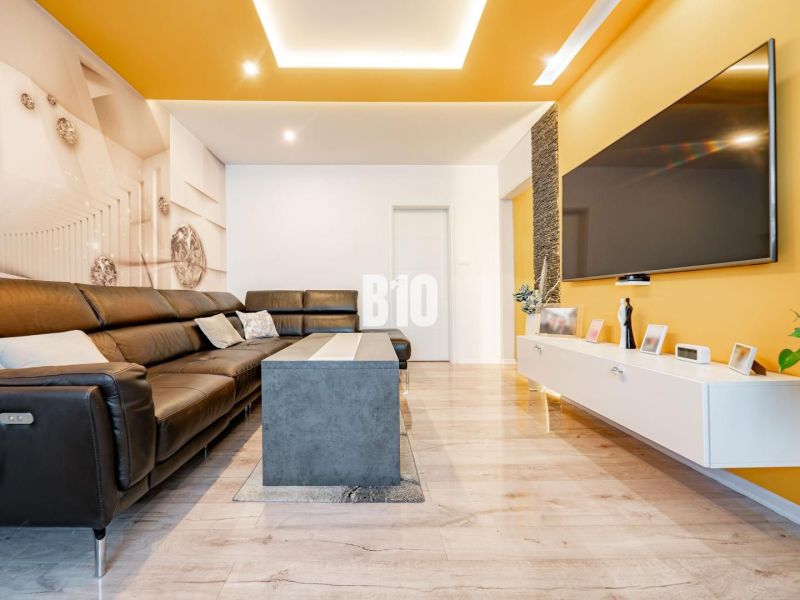 Living room in a 3-room apartment with a leather sofa set and a floor with a wood decor.