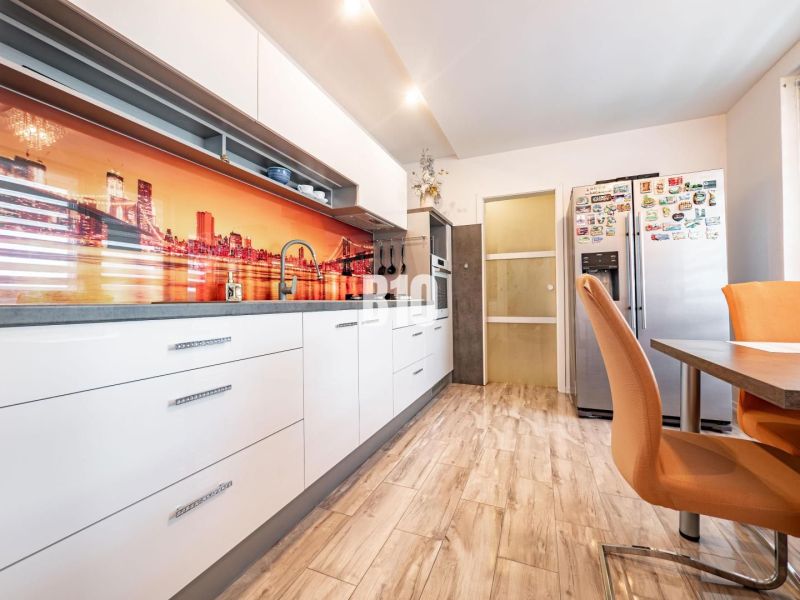 Kitchen in a 3-room apartment with a wooden decor floor and colorful wall wallpaper.