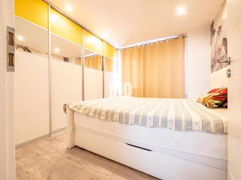 A bedroom in a three-room apartment with a wooden decor floor and a built-in wardrobe.