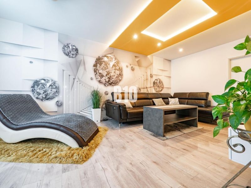 Living room of a three-room apartment with a comfortable sofa and a wooden-patterned floor.