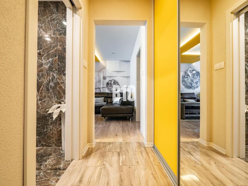 A hallway in a 3-room apartment with a wooden decor floor and yellow walls.