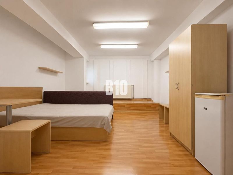 A bedroom in a two-room apartment with a wooden decor floor and simple furniture.
