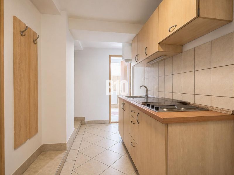 A kitchen with tiles and wooden cabinets in a two-room apartment.