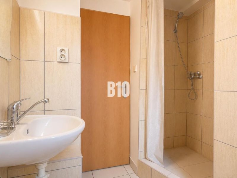 Bathroom with tiles and a shower in a 2-room apartment.