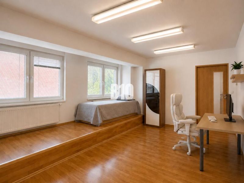 A spacious room in a 2-room apartment with a wooden decor floor and an office desk.