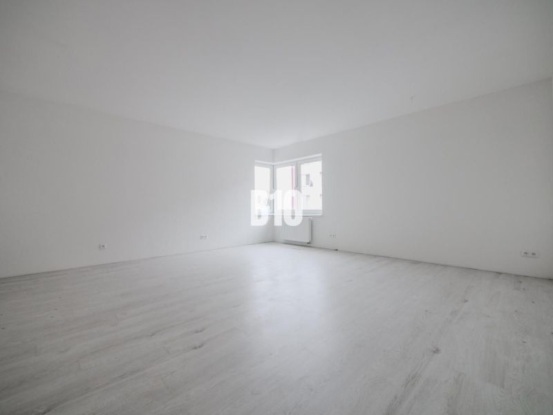 Empty room in a studio apartment with wood-patterned flooring.