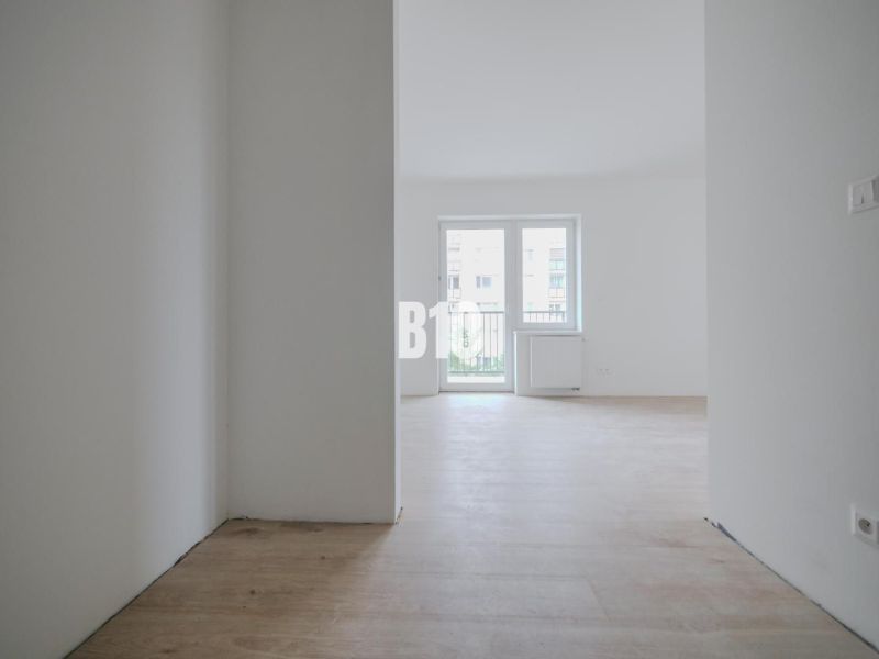 A bright room with a wooden decor floor in a studio apartment, window in the middle.