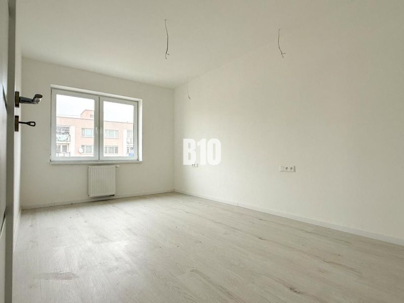 Interior of a 2-room apartment with a wooden decor floor, large window, and radiator.