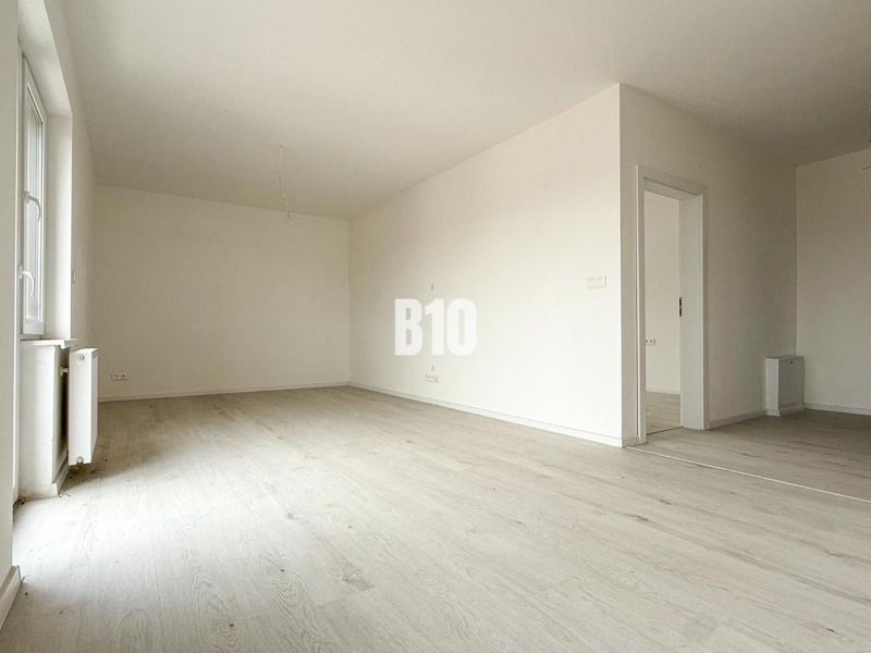 Spacious bright interior with wood-decor flooring in a 2-room apartment.