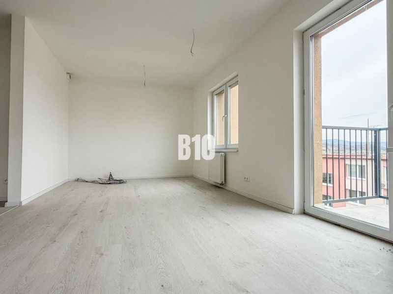 A bright living room with large windows and a wooden decor floor in a 2-room apartment.