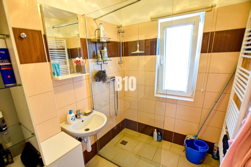 A bathroom in a cabin with a sink, a shower, and a window letting in light.
