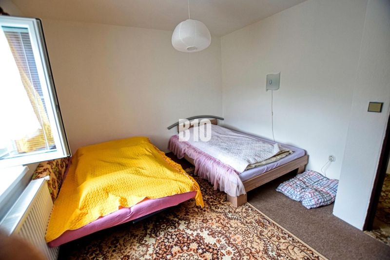 A room in a cottage with two beds, a white wall, and a carpet.