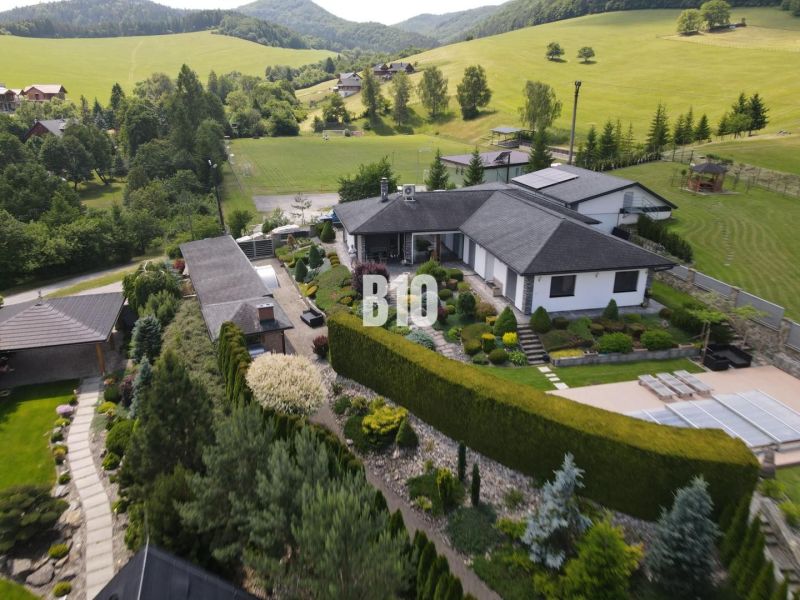 A family house in Súľov-Hradná with an ornamental garden and a view of the surrounding hills.