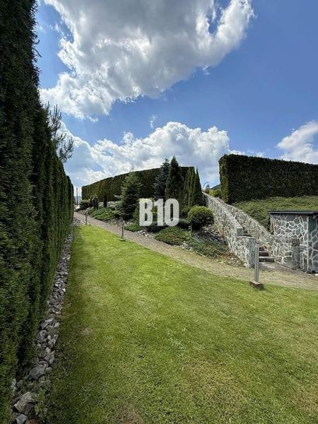 A garden at a family house in Súľov-Hradná with a well-maintained lawn and a hedge.